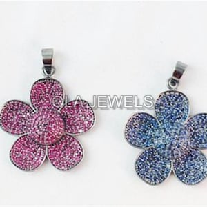 May include: Two silver flower pendants with crystal accents. One pendant is pink and the other is blue.