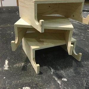May include: Three unfinished wooden shelves with cutouts on the sides, stacked on top of each other.