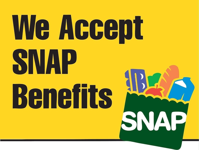 May include: A yellow sign with black text that reads "We Accept SNAP Benefits." A green grocery bag graphic is filled with groceries and the word "SNAP" is written on the bag.