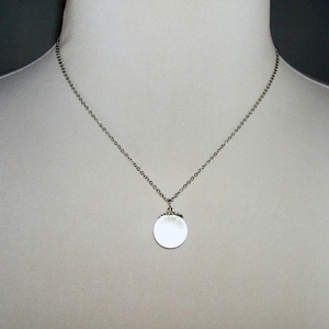 May include: A silver chain necklace with a round silver pendant.