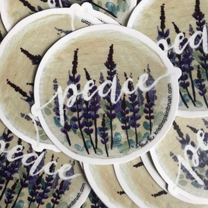 May include: Round sticker with a watercolor illustration of purple lavender flowers and the word "peace" in white script. The sticker has a white border and the website "kristinspaintbrush.com" is printed on the bottom right corner.