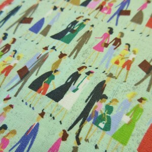 以下が含まれることがあります： 緑色の生地に、さまざまな色とスタイルの人々が繰り返しパターンで描かれています。人々はそれぞれ異なる服とアクセサリーを身に着けており、すべて一列に並んで立っています。