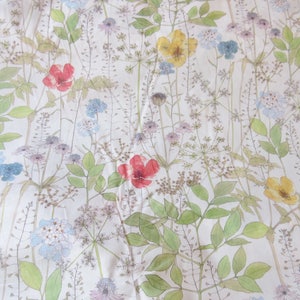 May include: A white fabric with a floral pattern featuring red, yellow, and blue flowers. The flowers are scattered throughout the fabric and are surrounded by green leaves.