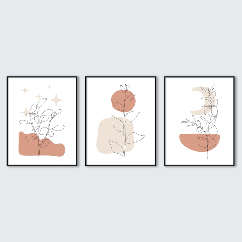 May include: Three minimalist line art prints with abstract shapes and foliage in shades of brown and beige. The prints are framed in black.