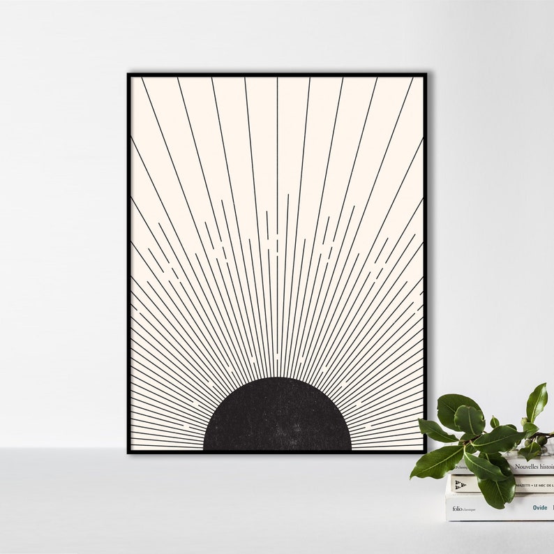 May include: A framed art print featuring a minimalist sunburst design. The artwork has a black semi-circle at the bottom, with black lines radiating upwards against a cream-colored background. The frame is black.