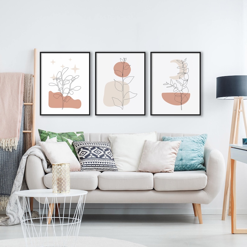 May include: Three minimalist line art prints with a neutral color palette. Each print features a branch with leaves and a geometric shape in shades of brown and beige.