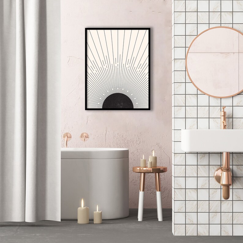 May include: A framed abstract art print featuring a black and white sunburst design. The artwork hangs above a modern bathtub in a bathroom setting. The bathroom has a pink wall, a white sink, and a round mirror.