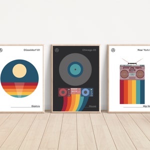 May include: Three framed art prints with minimalist designs. The prints feature a sunset, a vinyl record, and a boombox, each with a retro colour palette and text labels: 'Düsseldorf 81 Elektro', 'Chicago 85 House', and 'New York 88 Hip Hop'.