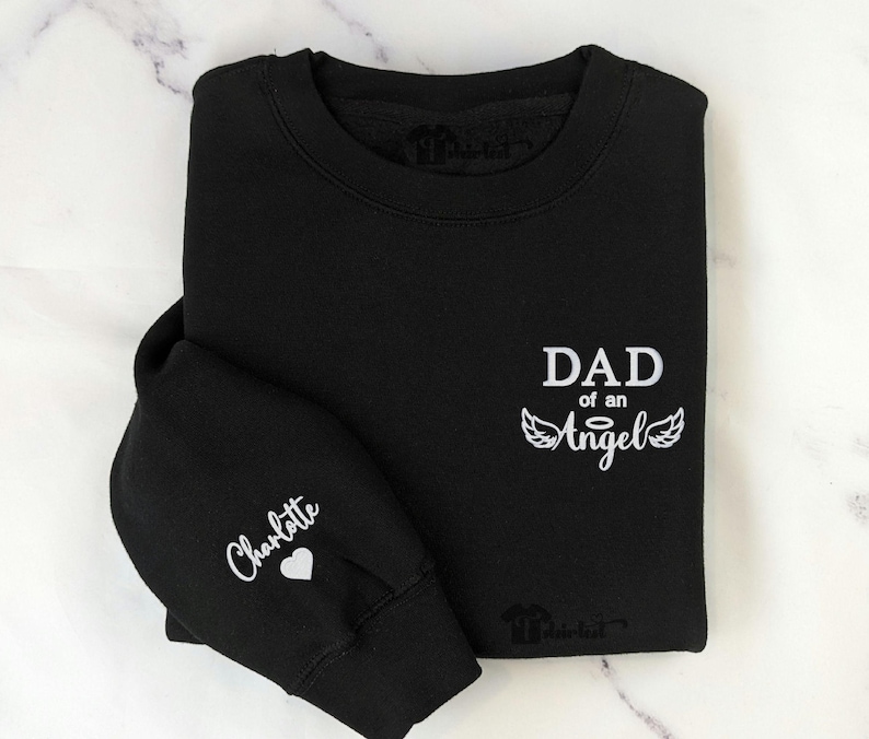 Custom embroidered “Dad of an Angel” sweatshirt with child’s name and heart on sleeve — personalized memorial gift for mom, dad, or grandparent, perfect Christmas remembrance hoodie or crewneck.