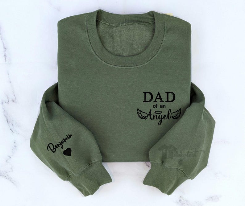 May include: Green sweatshirt with the text "DAD of an Angel" and a pair of angel wings. The left sleeve has the name "Benjamin" and a heart.