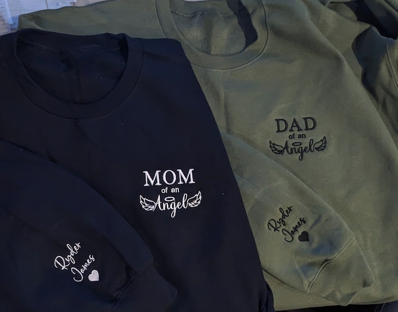 Custom embroidered “Mom Dad of an Angel” sweatshirt with child’s name and heart on sleeve — personalized memorial gift for mom, dad, or grandparent, perfect Christmas remembrance hoodie or crewneck.