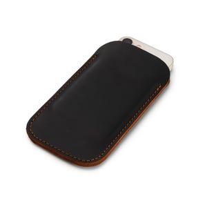 May include: Black leather phone case with a contrasting brown stitched border. The case is designed to hold a smartphone and is shown on a white background. The case is rectangular and has rounded corners.