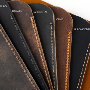 Op de afbeelding: Close-up van lederen swatches in verschillende kleuren, waaronder kastanje, matzwart, tabak, donkergroen, camel, zwart & tabak en licht tabak. De swatches zijn in een waaier vorm gerangschikt, met de stiksels zichtbaar op elk stuk.