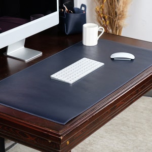 May include: A dark blue leather desk mat on a wooden desk with a white keyboard and mouse.