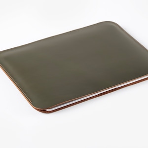 May include: A green leather laptop sleeve with a brown stitched edge.