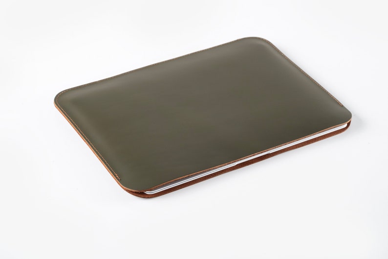 May include: A green leather laptop sleeve with a brown stitched edge.