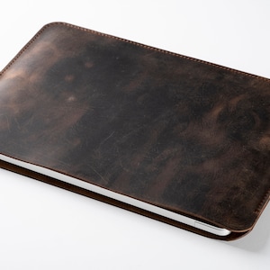 May include: A brown leather laptop sleeve with a distressed finish.