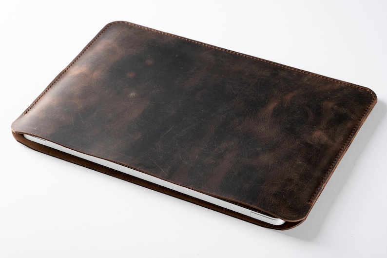 May include: A brown leather laptop sleeve with a distressed finish.