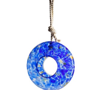 May include: A blue glass bird feeder shaped like a ring with a rope and hook for hanging. The glass is speckled with white and gold.