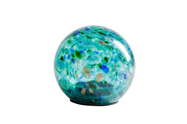 May include: A round glass globe with a swirling pattern of blue, green, and white. The globe is sitting on a black base.