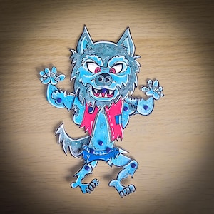 Può includere: Illustrazione di un lupo mannaro dei cartoni animati con pelliccia blu, occhi rossi e gilet rosso. Il lupo mannaro è in piedi con le braccia alzate e indossa pantaloncini blu. L'opera d'arte è su una superficie di legno.