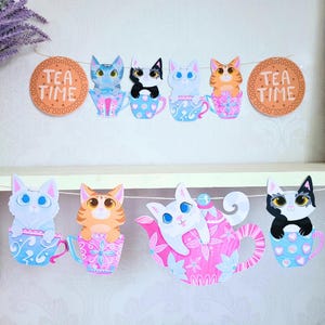 May include: A tea party banner with a string of colourful cats in teacups and a teapot. The banner has two tea time signs on either end.