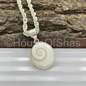 May include: A silver necklace with a pendant featuring a white, oval-shaped shell with a spiral design in the center. The chain is a twisted rope style. The pendant is approximately 1 inch in diameter.