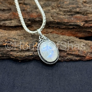 Può includere: Una collana d'argento con un ciondolo a forma di goccia. Il ciondolo presenta una grande pietra ovale iridescente incastonata in una lunetta d'argento con un motivo a corda ritorta. La catena è una catena a serpente d'argento.