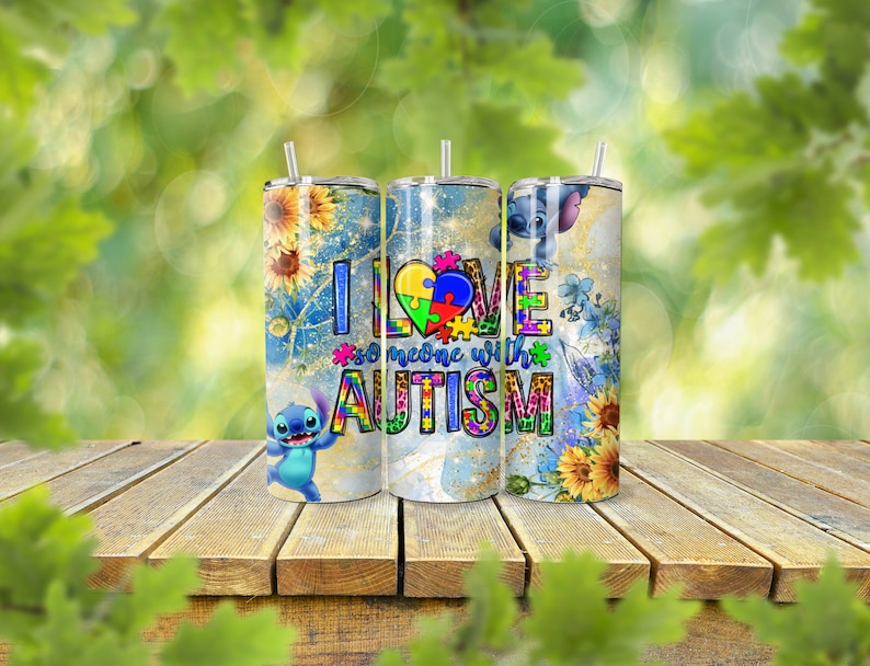 May include: Three stainless steel tumblers with lids and straws. Each tumbler features a design with sunflowers, the character Stitch, and the text "I love someone with autism". The tumblers are on a wooden surface.