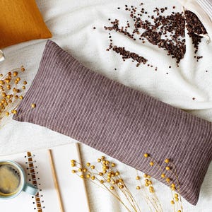 May include: A striped brown buckwheat pillow on a white background with a cup of coffee and a notebook. The pillow is made of natural fabric and is perfect for relaxation and sleep.