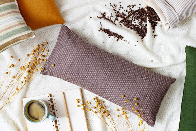 May include: A striped brown buckwheat pillow on a white background with a cup of coffee and a notebook. The pillow is made of natural fabric and is perfect for relaxation and sleep.