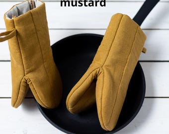 May include: Two mustard yellow oven mitts with a quilted design. The mitts are made of a thick, durable fabric and are perfect for protecting your hands from heat.