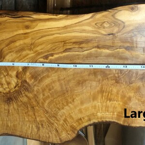 Puede incluir: Una tabla de servir de madera natural grande con una forma org&aacute;nica &uacute;nica. La tabla mide aproximadamente 45 cm de largo y tiene un hermoso patr&oacute;n de grano. La palabra "Large" est&aacute; escrita en la tabla.