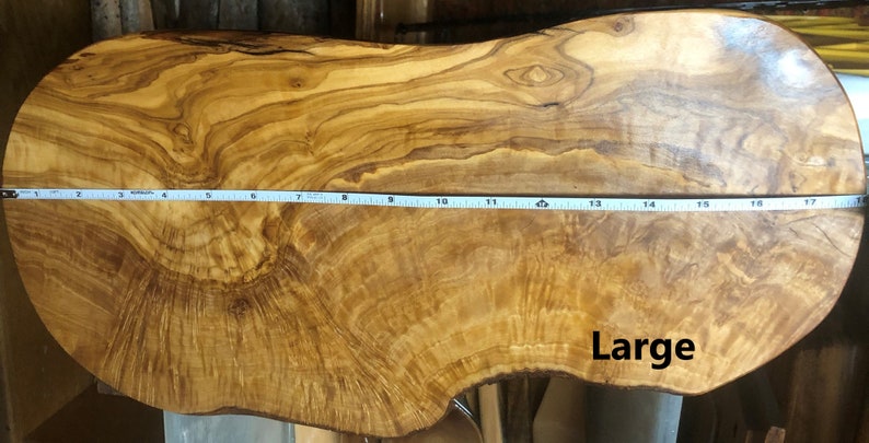Puede incluir: Una tabla de servir de madera natural grande con una forma org&aacute;nica &uacute;nica. La tabla mide aproximadamente 45 cm de largo y tiene un hermoso patr&oacute;n de grano. La palabra "Large" est&aacute; escrita en la tabla.