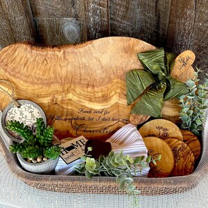 Puede incluir: Una bandeja de servir de madera con un acabado de grano de madera natural. La bandeja est&aacute; llena de una variedad de art&iacute;culos, incluyendo una peque&ntilde;a suculenta en maceta, un lazo verde, un letrero de madera que dice "Home Sweet Home" y varios posavasos de madera peque&ntilde;os con dise&ntilde;os grabados. La bandeja est&aacute; sentada sobre una superficie tejida.
