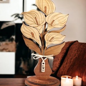 May include: Wooden cutout of a bouquet of calla lilies in a vase with a personalized tag that says "R & D" and a base that says "Love Blooms Here".