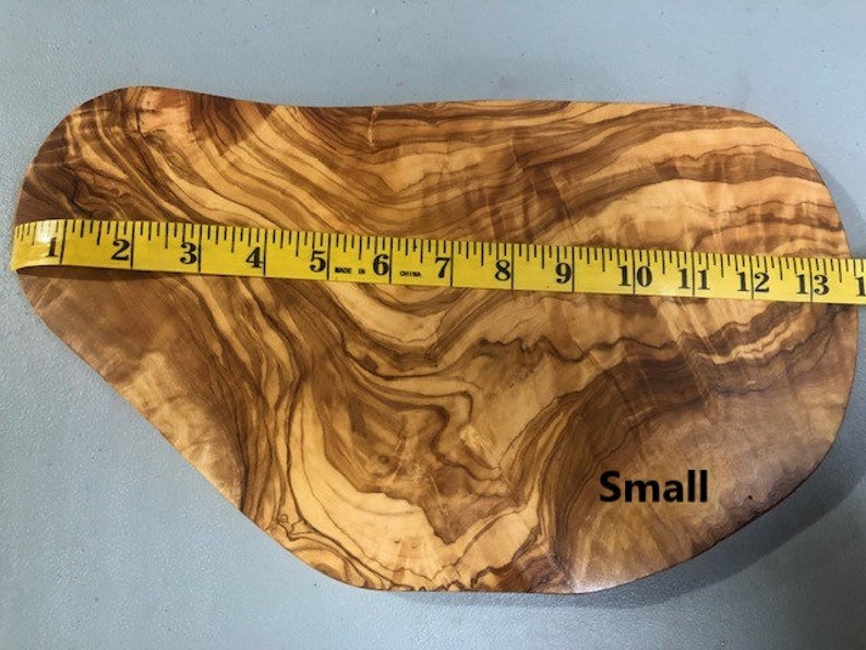 Puede incluir: Una peque&ntilde;a tabla de servir de madera natural con una forma org&aacute;nica &uacute;nica. La tabla est&aacute; hecha de madera de olivo y tiene un color marr&oacute;n intenso con un patr&oacute;n de veta natural. La tabla mide aproximadamente 33 cm de largo y tiene la palabra "Small" escrita en ella.