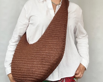 May include: A brown hobo-style shoulder bag crafted with a dense, textured crochet knit pattern. The bag features a wide, integrated strap that rests comfortably across the body, showcasing a deep, solid brown color and a curved, slouchy silhouette.