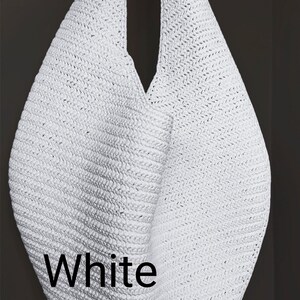 May include: A white hobo-style shoulder bag crafted from a woven, textured material. The bag features a single integrated strap and a slouchy, teardrop-shaped silhouette. The word White is printed in black sans-serif text on the lower left side.