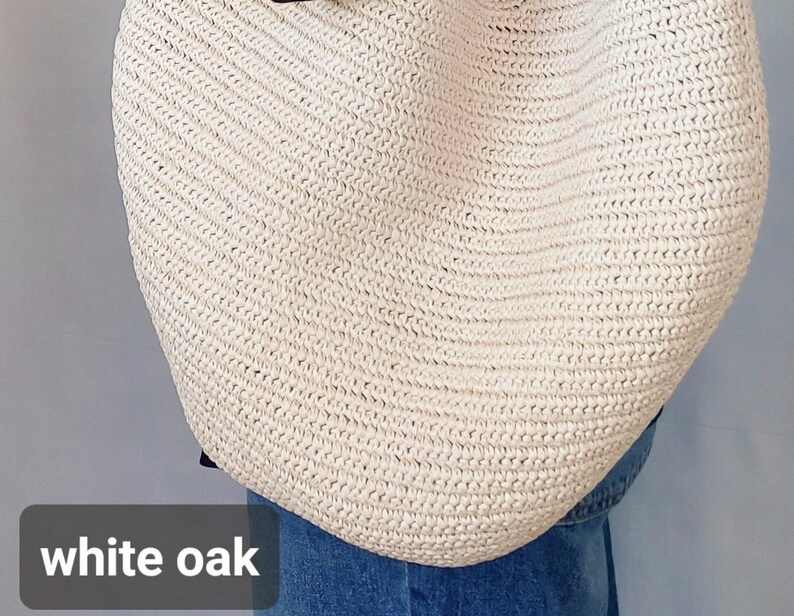 May include: A large, off-white woven straw tote bag with a textured, braided pattern. The bag features a rounded, slouchy silhouette and is positioned against a plain background. The text white oak is visible in the bottom left corner.