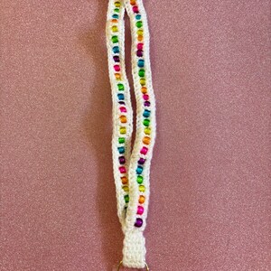 May include: White crocheted lanyard with a rainbow of beads and a silver key ring.