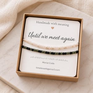 May include: Two beaded bracelets in a cardboard box. One bracelet has white beads, the other has dark green beads. The display card reads: Handmade with meaning, Until we meet again, Morse Code, and the website address timelesselegance3.com.