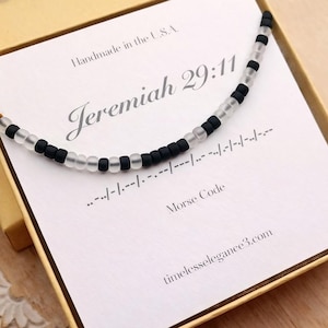 May include: A beaded necklace with alternating black and clear beads, presented in a gift box. The necklace is displayed on a card with the text "Jeremiah 29:11" and Morse code. The box also includes the text "Handmade in the U.S.A."