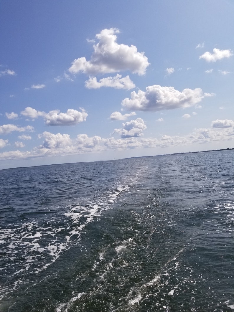 Puede incluir: Vista de un cielo azul con nubes blancas y una estela en el agua de un barco.