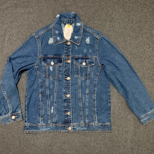 Op de afbeelding: Een blauw denim jack met distressed details en een knoopsluiting.