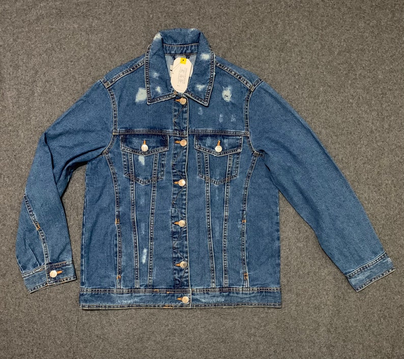 Op de afbeelding: Een blauw denim jack met distressed details en een knoopsluiting.