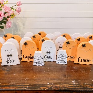 Pu&ograve; includere: Una collezione di 14 decorazioni in legno a forma di fantasma di colore arancione e bianco con fiocchi neri e volti dipinti. I fantasmi sono decorati con nomi, tra cui "Sofia", "Koa", "Gus", "Finley", "Atlas", "Gracie" e "Lizzie".