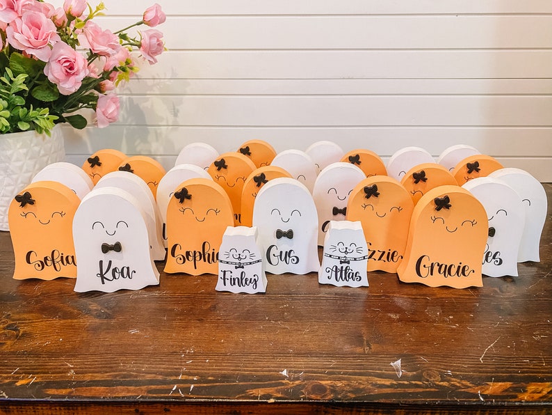 Pu&ograve; includere: Una collezione di 14 decorazioni in legno a forma di fantasma di colore arancione e bianco con fiocchi neri e volti dipinti. I fantasmi sono decorati con nomi, tra cui "Sofia", "Koa", "Gus", "Finley", "Atlas", "Gracie" e "Lizzie".