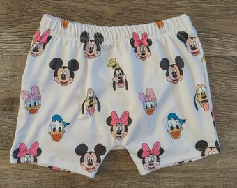 May include: White shorts with a pattern of Mickey Mouse, Minnie Mouse, Donald Duck, Goofy, and Pluto characters.