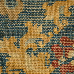 May include: Close-up of a woven tapestry with a blue, red, and yellow floral pattern.